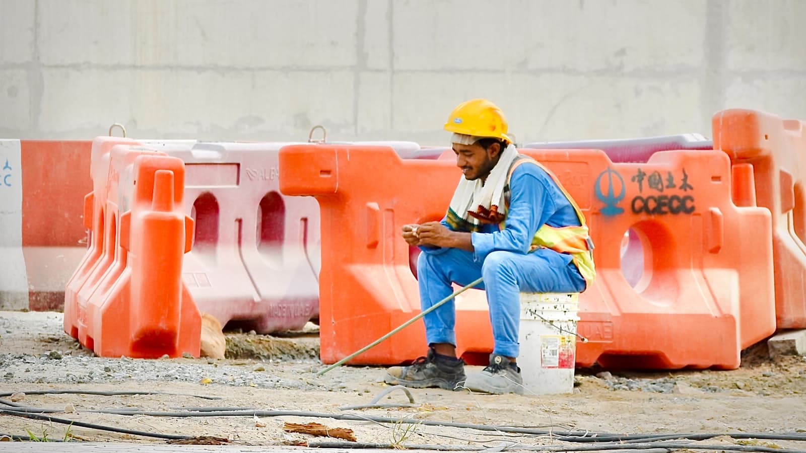 Un trabajador con casco y chaleco de alta visibilidad usando el móvil en la instalación